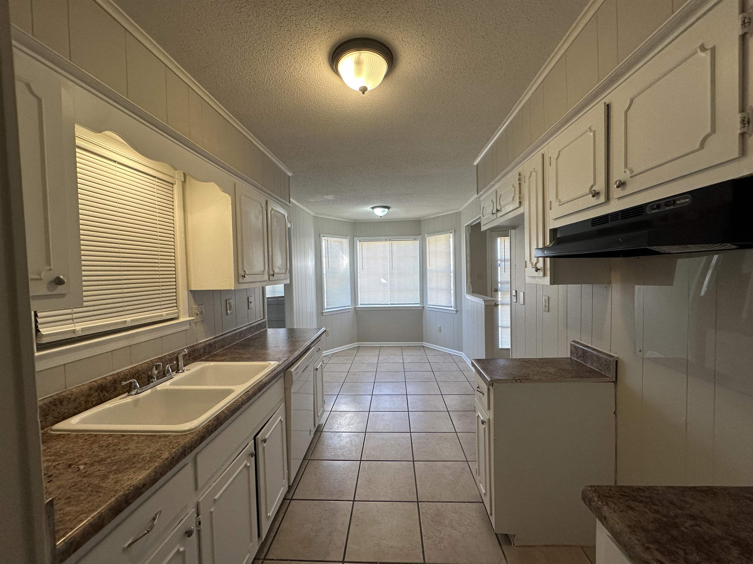 1931 Stone Bridge Drive Memphis, TN 38134 - Photo 14 of 16 Kitchen with crown molding, dark countertops, under cabinet range hood, a textured ceiling, and light tile patterned floors