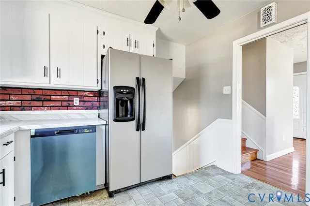 a kitchen with stainless steel appliances a refrigerator a stove and white cabinets