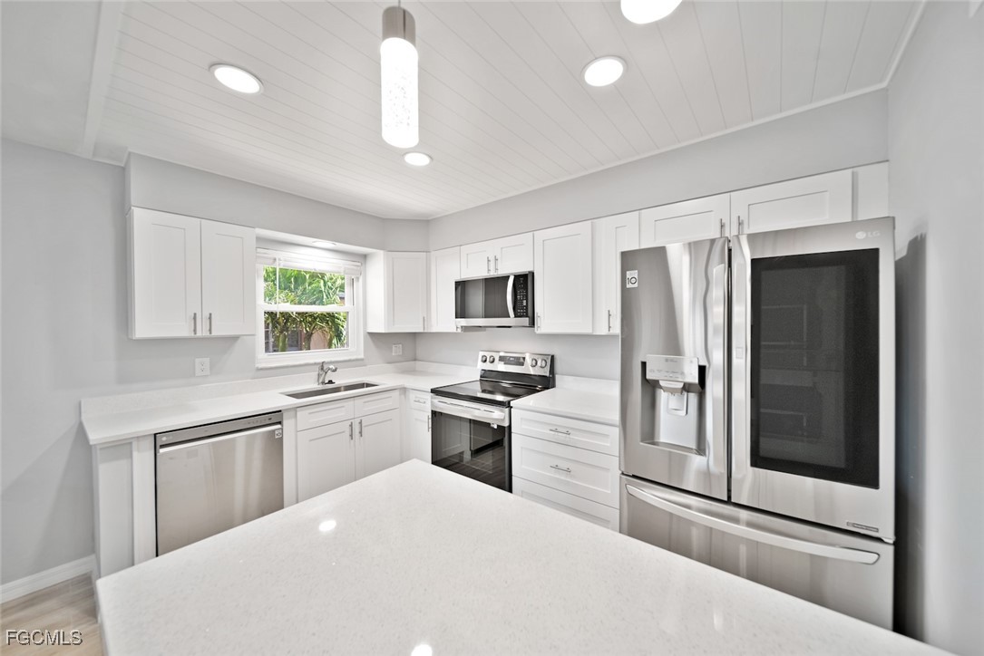 16881 Davis Road, Unit 721 Fort Myers, FL 33908 - Photo 9 of 23 a kitchen with stainless steel appliances granite countertop a refrigerator a stove a sink dishwasher a oven with white cabinets and wooden floor
