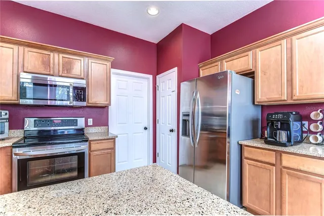 a kitchen with stainless steel appliances kitchen island granite countertop a refrigerator stove and sink