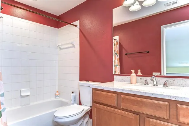 a bathroom with a granite countertop bathtub sink vanity mirror and toilet