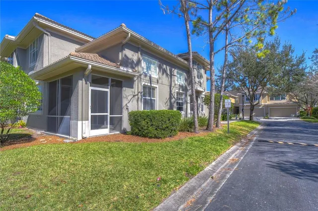 a view of a house with brick walls plants and large tree