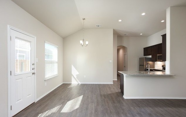 3414 Scott Circle Seguin, TX 78155 - Photo 3 of 12 Kitchen featuring dark wood finish cabinetry, arched walkways, dark wood finished floors, light stone countertops, and vaulted ceiling