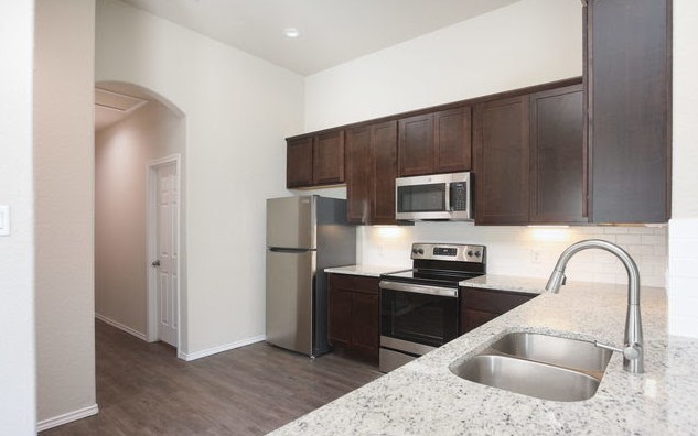 3414 Scott Circle Seguin, TX 78155 - Photo 4 of 12 Kitchen featuring dark wood finish cabinets, stainless steel appliances, arched walkways, and light stone countertops