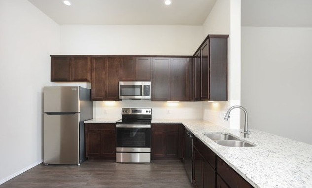 3414 Scott Circle Seguin, TX 78155 - Photo 5 of 12 Kitchen featuring stainless steel appliances, dark wood finish cabinets, light stone counters, dark wood-style floors, and recessed lighting
