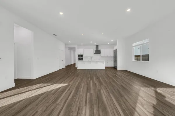 a view of kitchen and empty room with wooden floor