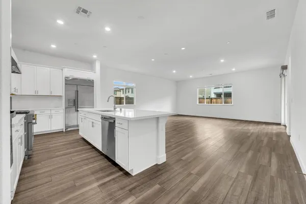 a kitchen with kitchen island wooden floors appliances and cabinets