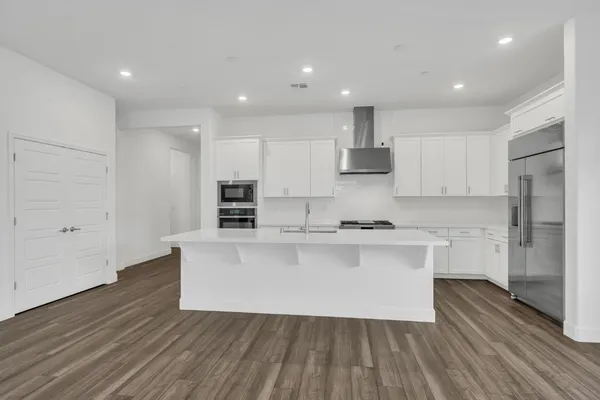 a large kitchen with stainless steel appliances granite countertop a stove a sink and white cabinets