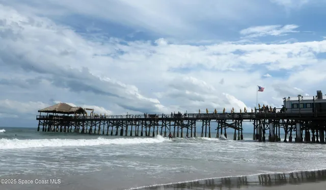 a view of swimming pool with lawn chairs and large trees