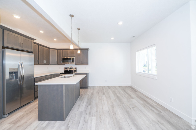 46 West 460 Smithfield, UT 84335 - Photo 6 of 31 Open-concept kitchen featuring gray cabinetry, stainless steel appliances, a central island with an undermount sink, pendant lighting, and wood-finish flooring