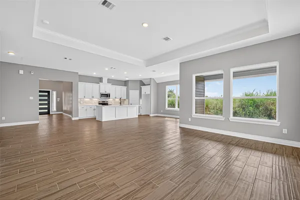 a view of an empty room with a window and wooden floor