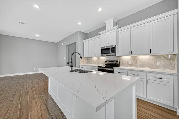 a kitchen with sink a microwave and cabinets