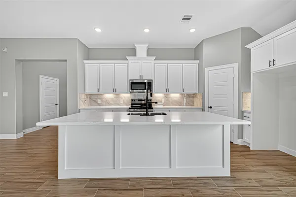 a kitchen with kitchen island white cabinets and stainless steel appliances