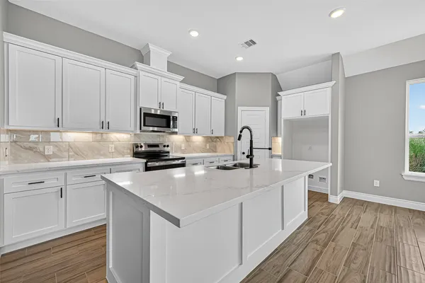 a kitchen with sink a microwave and cabinets