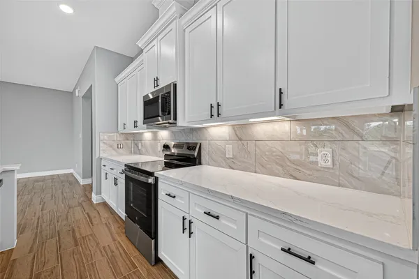 a kitchen with granite countertop cabinets stainless steel appliances and wooden floor
