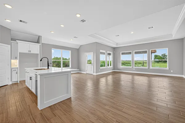 a large white kitchen with wooden floors and stainless steel appliances