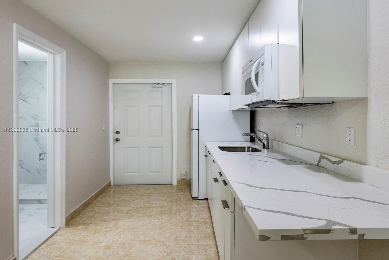 10770 Southwest 26th Street Miami, FL 33165 - Photo 21 of 35 a room with a sink a refrigerator and cabinets