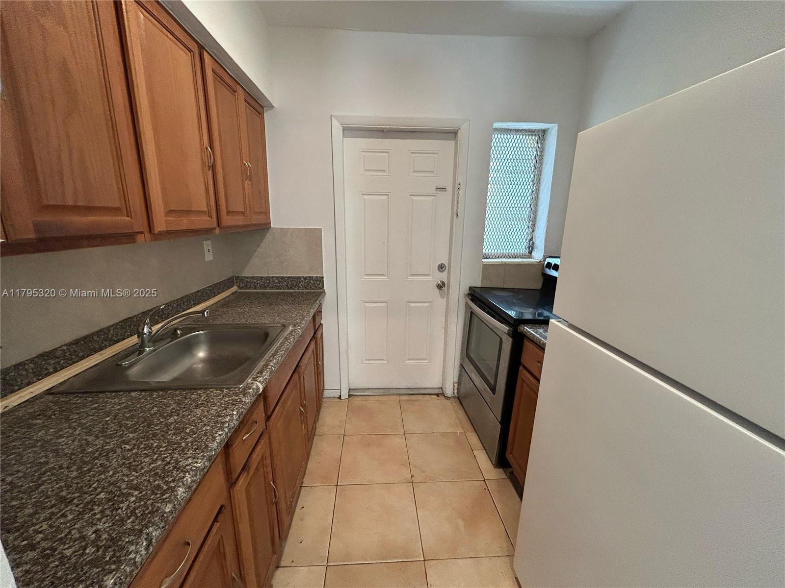 8321 Crespi Boulevard, Unit 1 Miami Beach, FL 33141 - Photo 4 of 15 a kitchen with a sink stove and cabinets