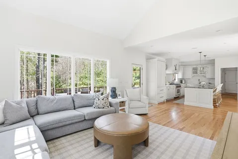 a kitchen with stainless steel appliances a table chairs in it white cabinets and a wooden floor