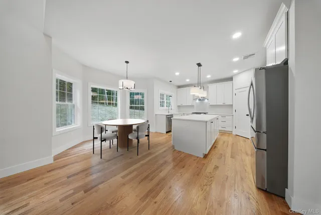 a large kitchen with stainless steel appliances sink a stove a refrigerator and a oven with wooden floor