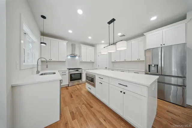 a large kitchen with kitchen island a large window a sink stainless steel appliances and cabinets