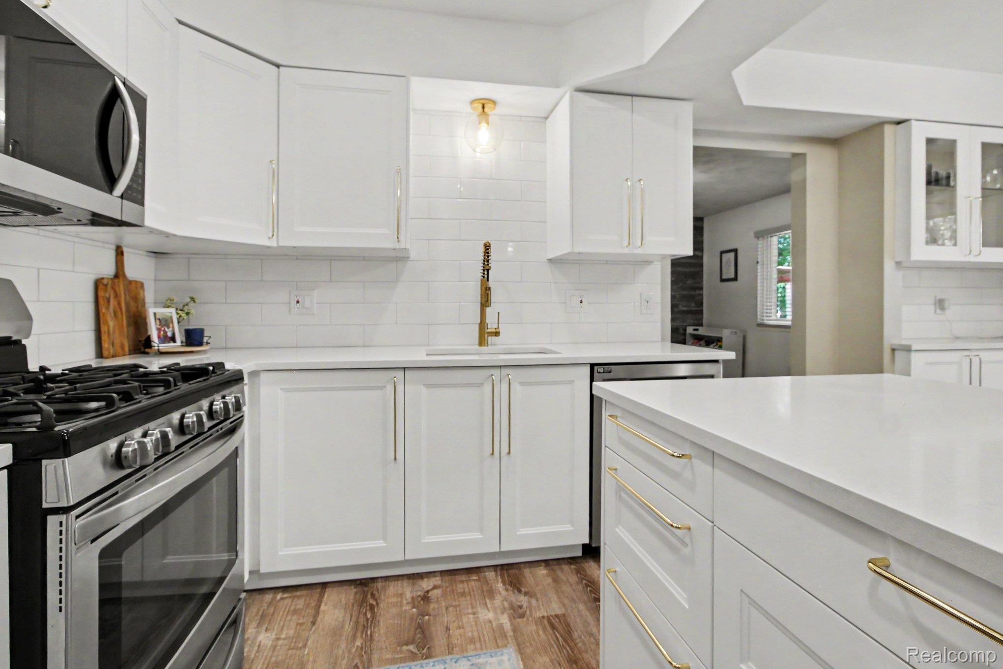 7235 Iron Gate Road Canton, MI 48187 - Photo 7 of 27 Kitchen featuring white cabinetry with gold-toned hardware, white subway tile backsplash, and light-toned countertops