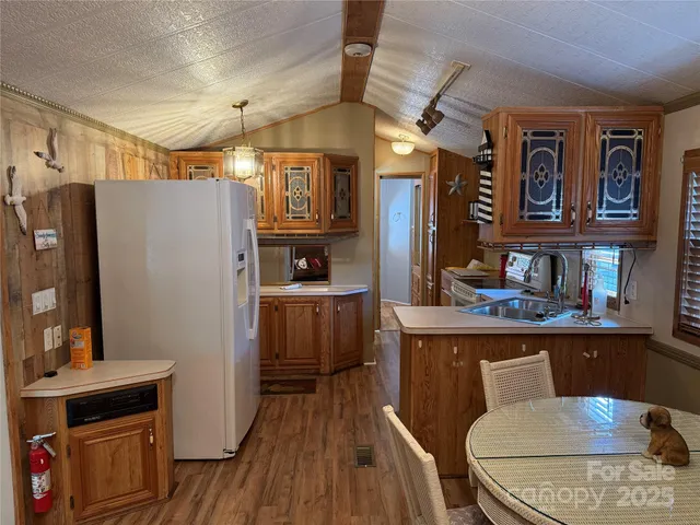 a kitchen with stainless steel appliances a stove a refrigerator a sink a dining table and chairs with wooden floor
