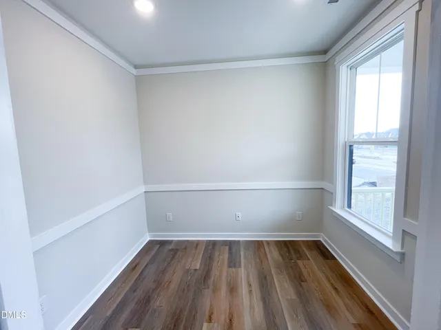 a view of an empty room with wooden floor and window