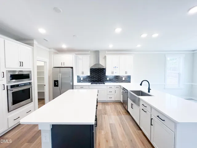 a large white kitchen with wooden floor