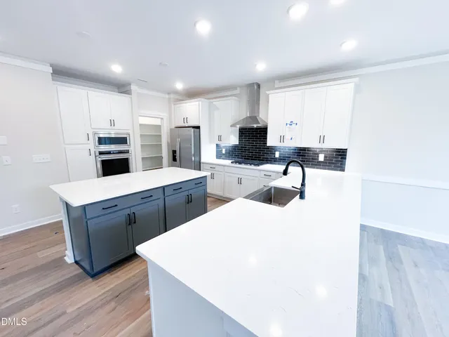 a large white kitchen with stainless steel appliances kitchen island a large counter top a stove and a sink