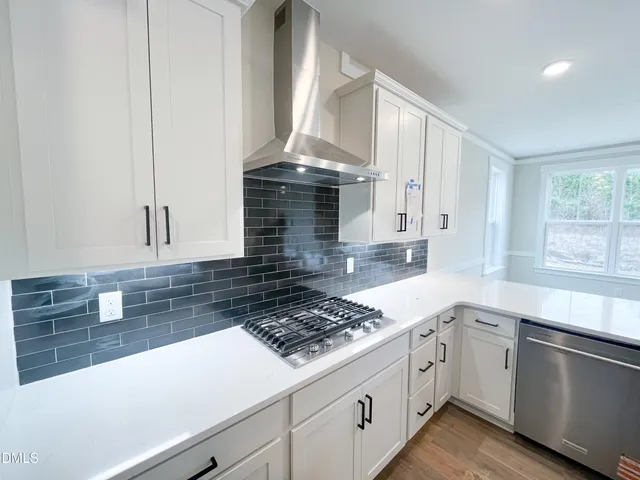 a view of an empty room with wooden floor and a fireplace