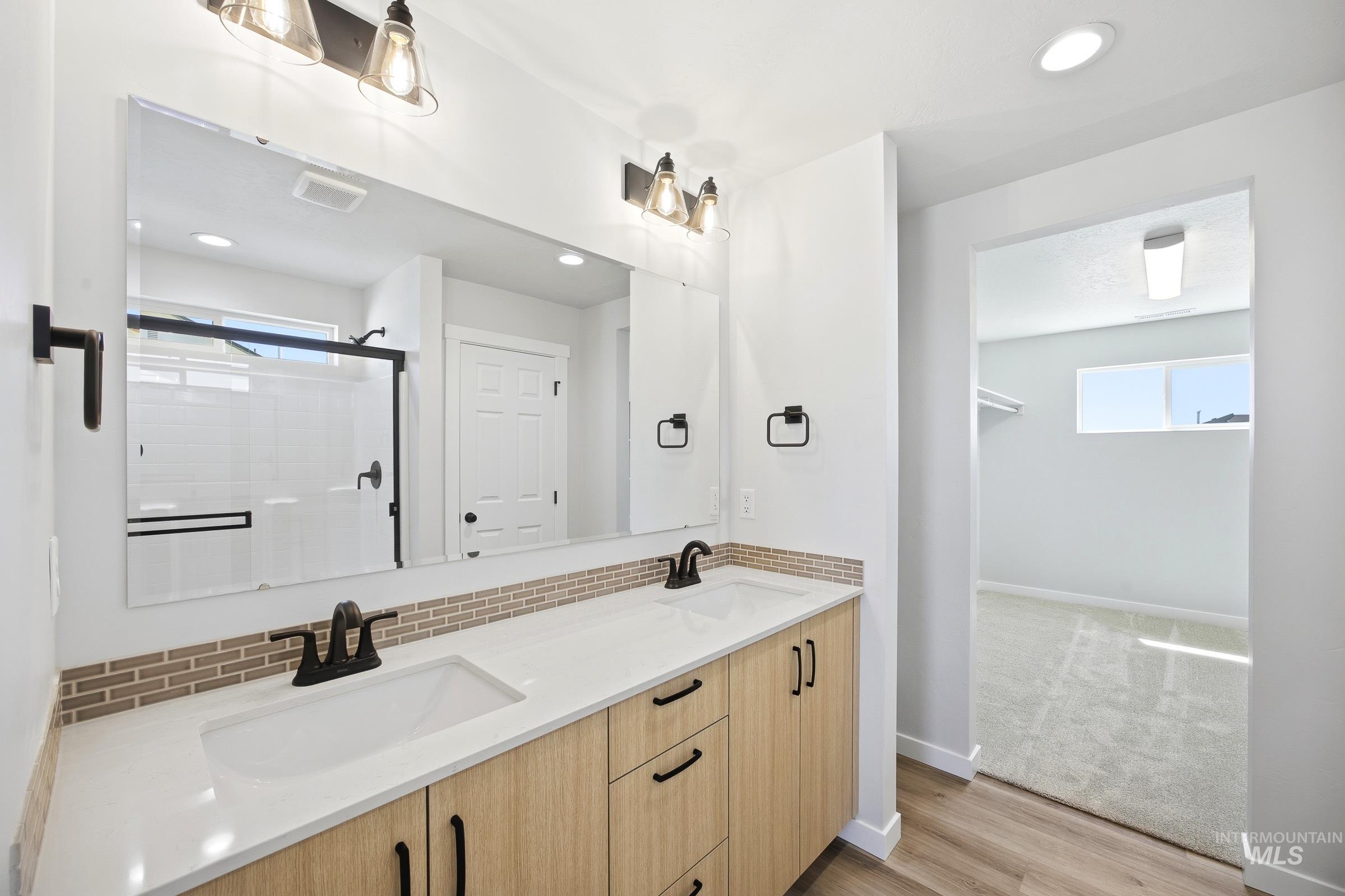 12841 Decatur Street Nampa, ID 83651 - Photo 27 of 30 Double vanity with white countertops, light wood-finish cabinetry, and black hardware