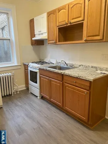 a kitchen with granite countertop wooden cabinets stainless steel appliances and a window