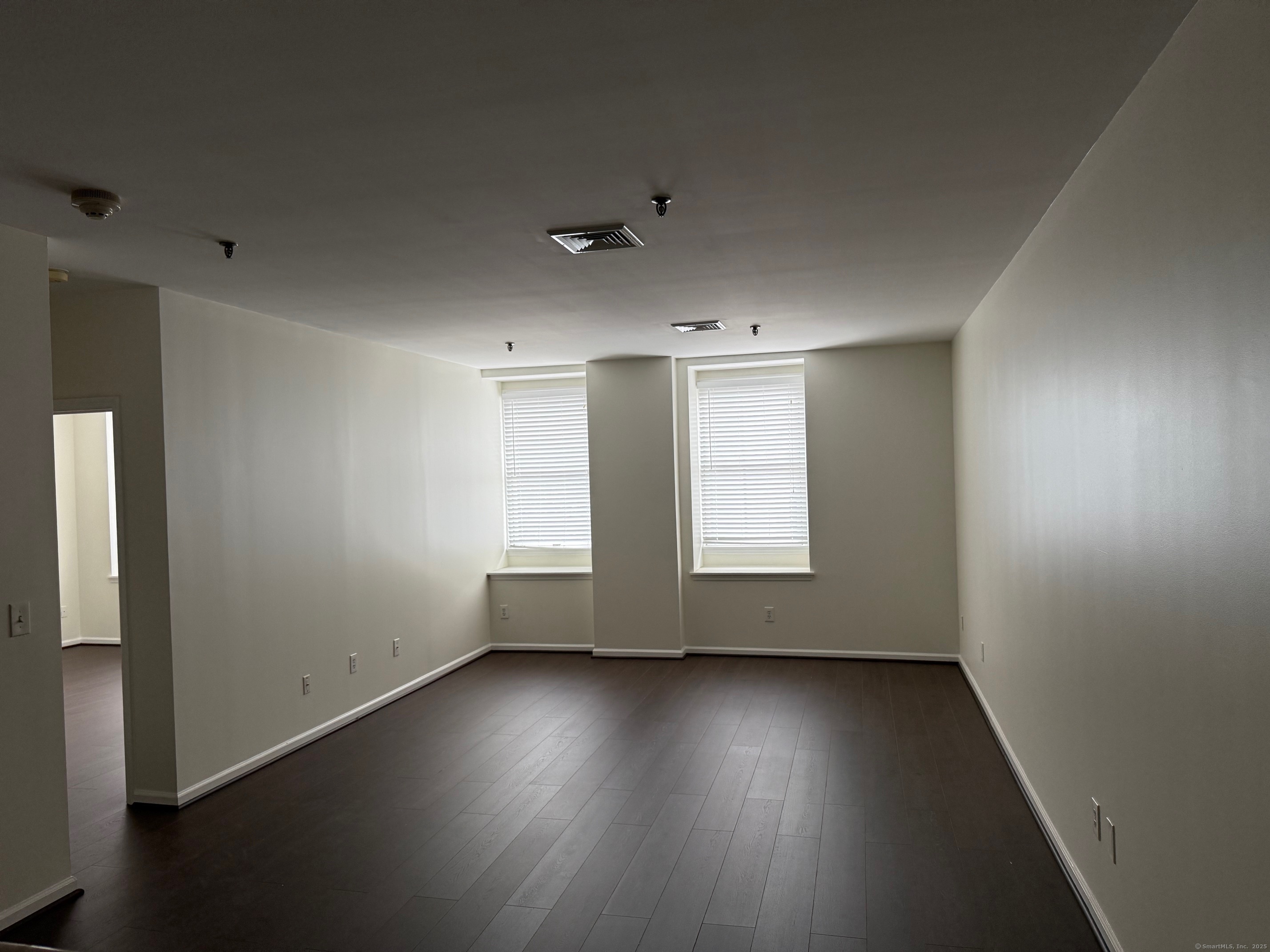 84 Wall Street Norwalk, CT 06850 - Photo 4 of 5 an empty room with wooden floor and windows with curtains