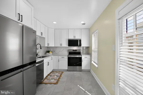 a kitchen with granite countertop appliances a sink and a refrigerator
