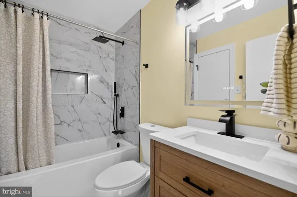 a bathroom with a sink a toilet a mirror and shower