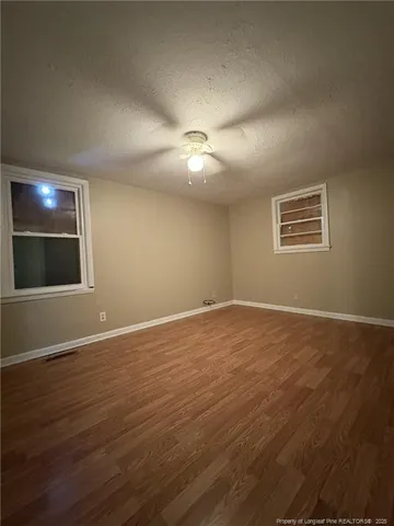 a view of an empty room with window and wooden floor