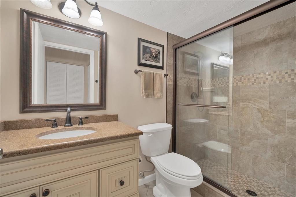 5032 Marsh Field Road, Unit 19 Sarasota, FL 34235 - Photo 15 of 30 a bathroom with a granite countertop toilet a sink a mirror a vanity and shower