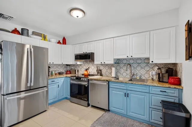 a kitchen with stainless steel appliances granite countertop a refrigerator sink and white cabinets