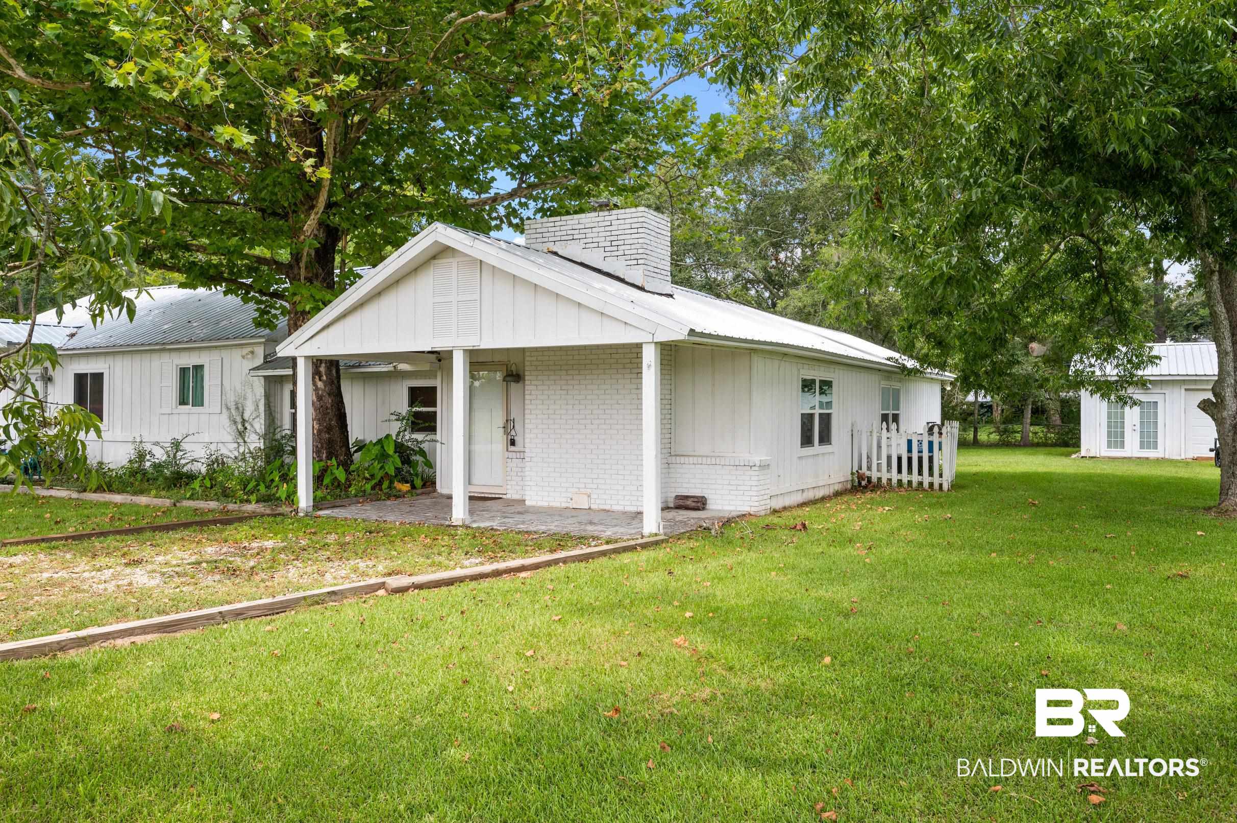 24663 Chestnut Street Elberta, AL 36530 - Photo 3 of 22 White exterior featuring a covered front porch, a brick chimney, and a metal roof
