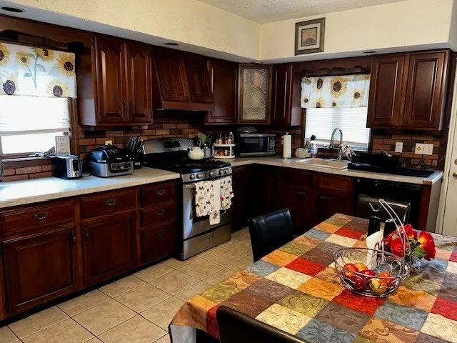 a kitchen with stainless steel appliances granite countertop a sink dishwasher stove and cabinets