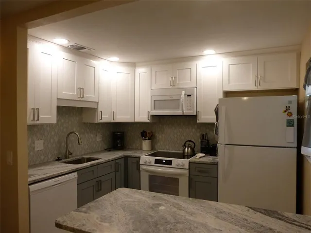 a kitchen with a refrigerator sink and white cabinets
