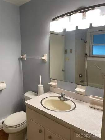 a bathroom with a granite countertop sink toilet and mirror