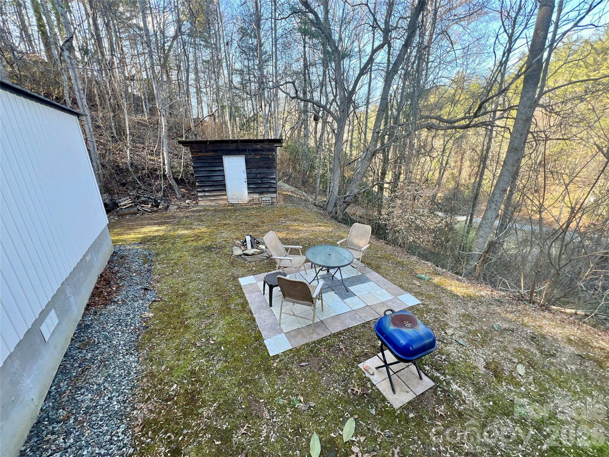 1019 Hudlin Gap Road Pisgah Forest, NC 28768 - Photo 5 of 24 a view of a backyard with table and chairs with wooden fence and plants