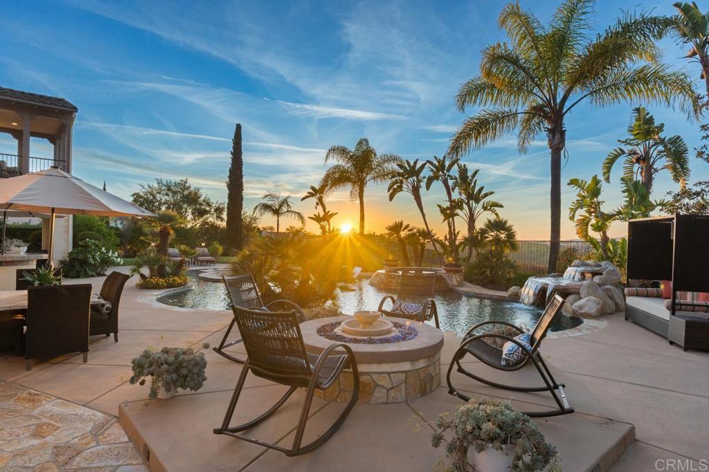 14844 Whispering Ridge Road San Diego, CA 92131 - Photo 40 of 73 a view of a patio with a dining table and chairs under an umbrella with potted plants
