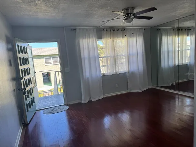 a view of empty room with wooden floor and fan