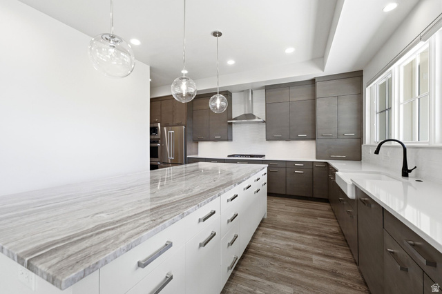496 North Farmhouse Way, Unit 11 Midway, UT 84049 - Photo 19 of 50 Contemporary kitchen featuring a stone-top island with extensive drawer storage, wood-finish flooring, dark-toned cabinetry, and a white farmhouse sink with a matte black faucet