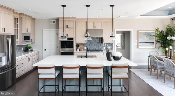 a kitchen with stainless steel appliances kitchen island granite countertop a dining table chairs and a refrigerator