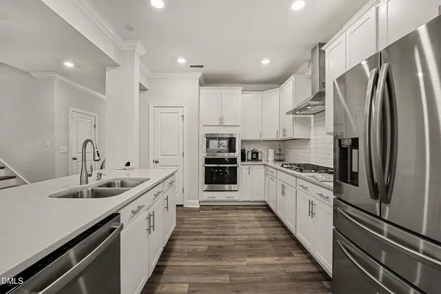 a large kitchen with stainless steel appliances kitchen island granite countertop a refrigerator and a sink