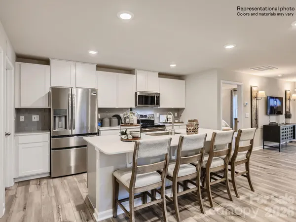 a kitchen with a dining table chairs refrigerator and microwave
